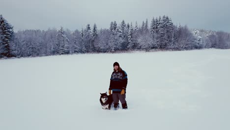 man and alaskan malamute dog in snow during wintertime in norway