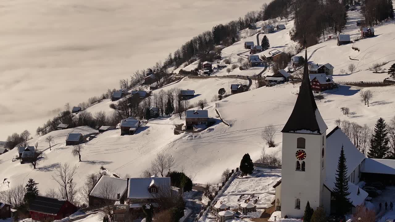 Close-up aerial view of Amden, Switzerland, featuring its iconic church with a clock tower, surrounded by heavy snow during the extreme Swiss winter.
