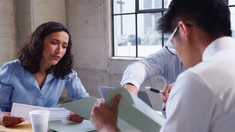 Three-young-professionals-in-discussion-at-a-meeting