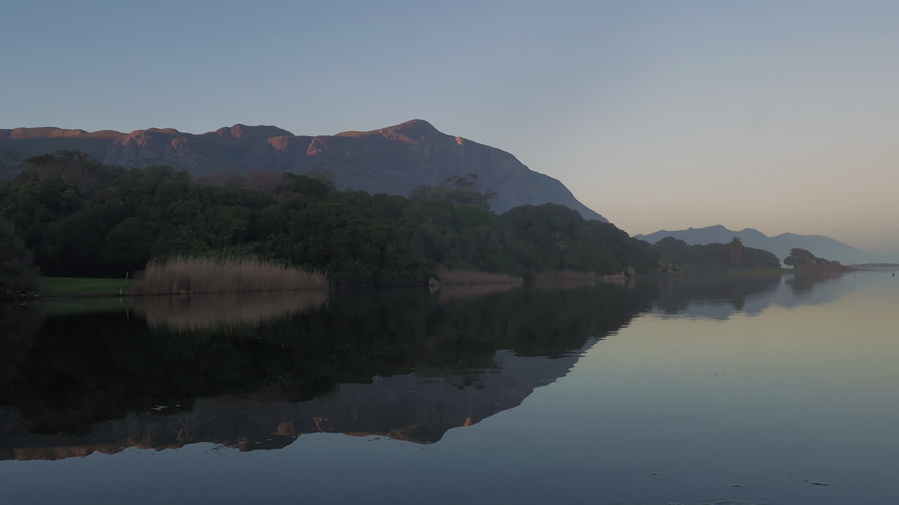 석호의 매끄러운 표면에 산과 숲의 반사, 틸트 업 샷