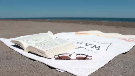 open book on a towel lying on a sunny beach the wind is flipping the pages 1