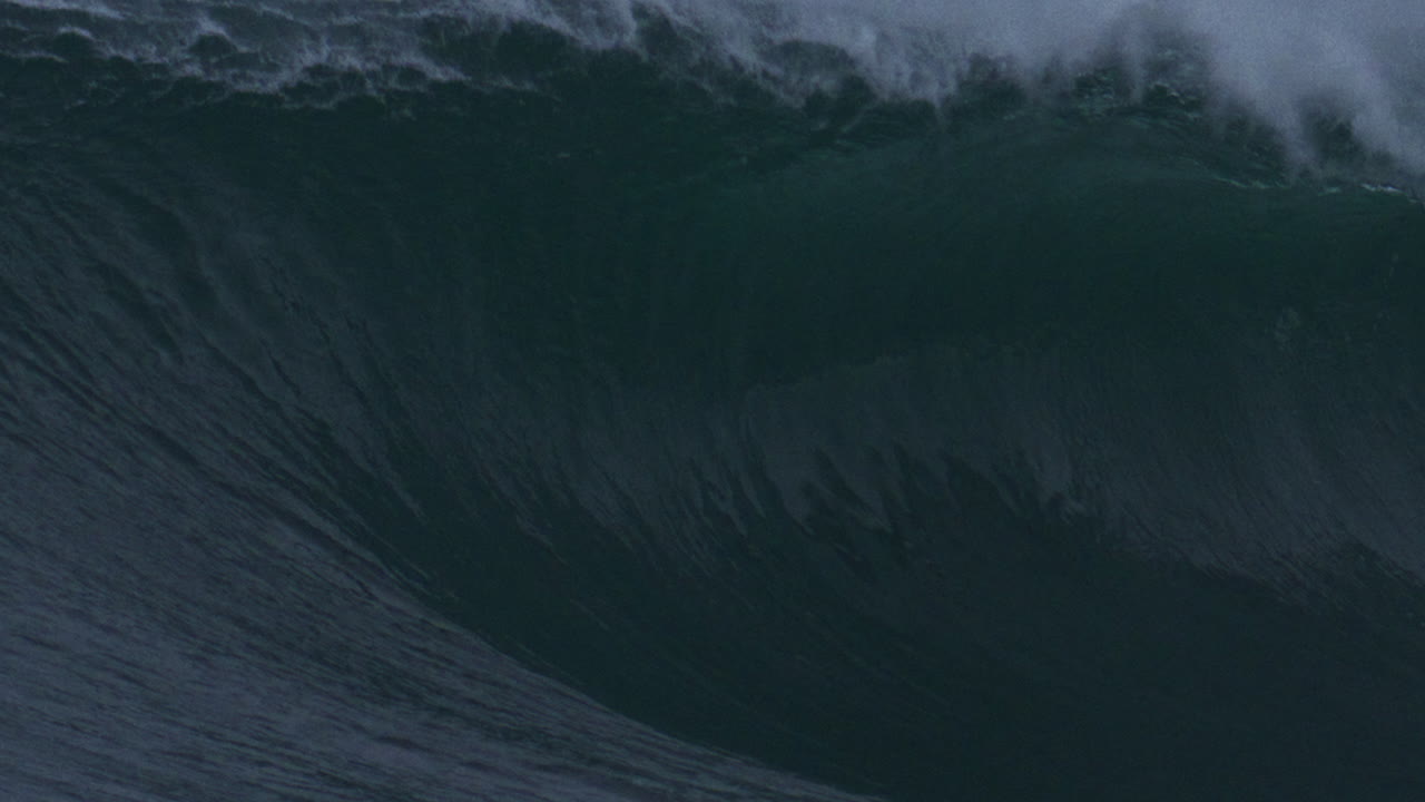 Detailed texture view of ocean wave lip curling as mist rises off top