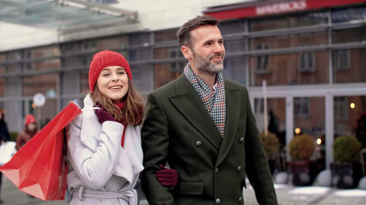 길거리를  ⁇ 고 있는 쇼핑 가방 을 가진 성숙 한 부부