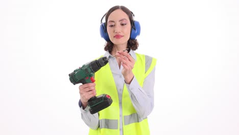 woman in safety vest and ear defenders with a power drill