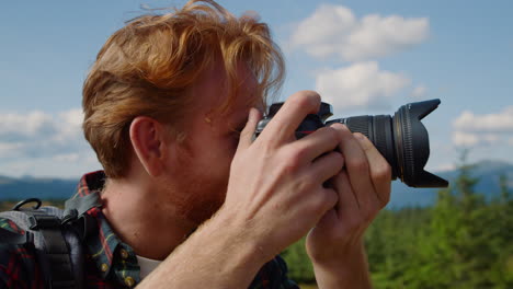 un tipo sonriente tomando fotos del paisaje con una cámara profesional