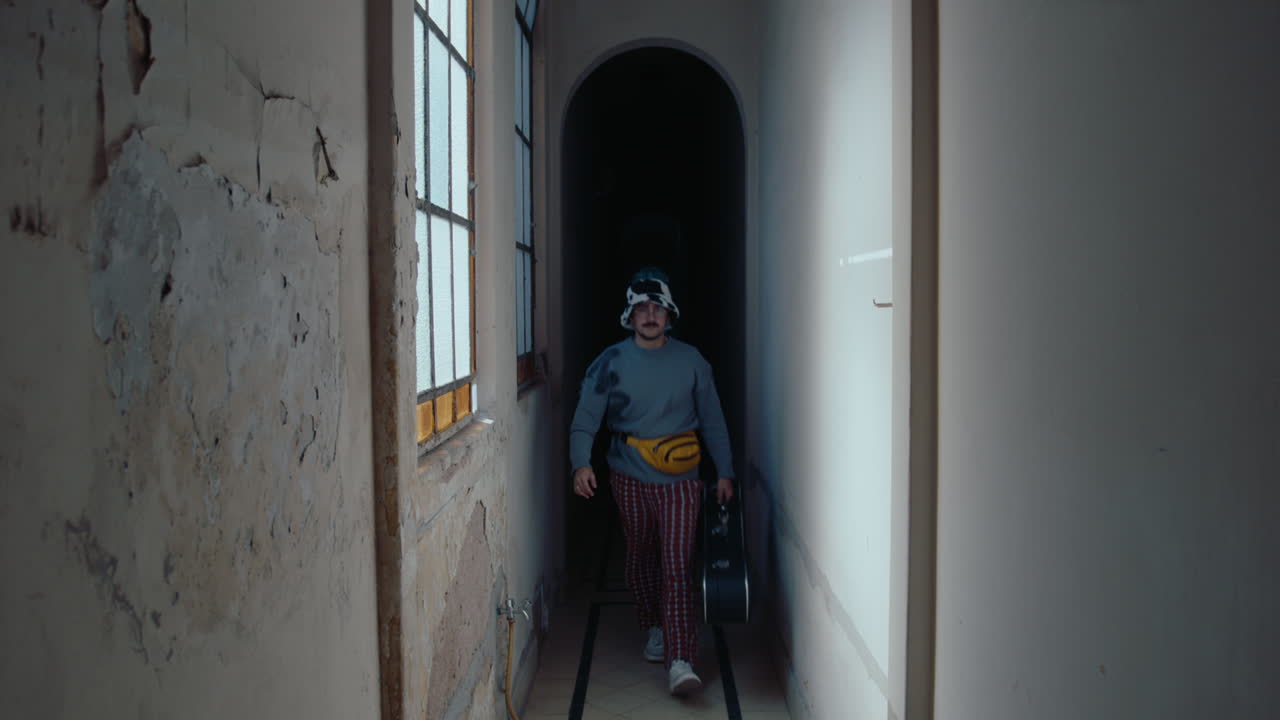 Man with Guitar Walking through Corridor in Old Apartment Building