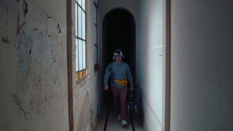man with guitar walking through corridor in old apartment building
