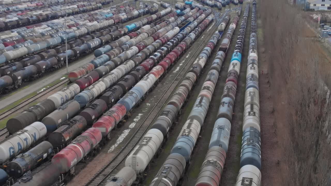 Treni e vagoni merci disposti in file in uno scalo ferroviario in una città.