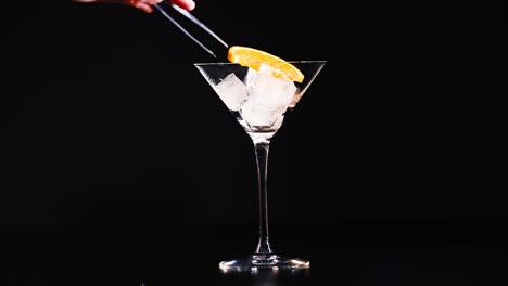 hielo y rebanada de naranja en un vaso de martini.