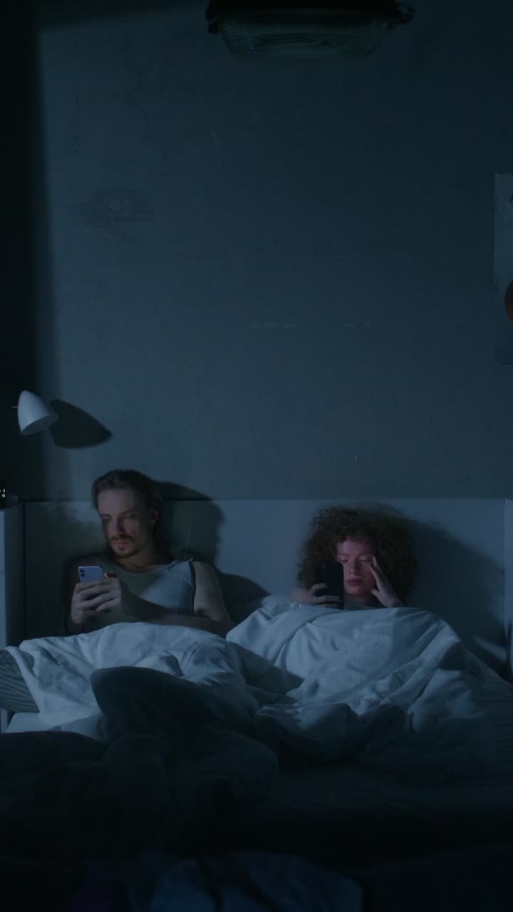 pareja usando teléfonos en la cama por la noche