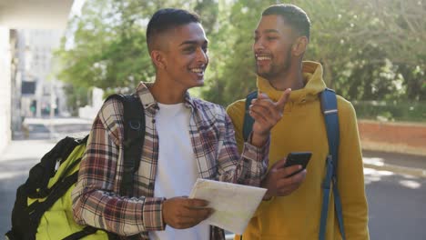 Zwei-Glückliche-Männliche-Freunde-Gemischter-Abstammung,-Die-Smartphone-Und-Karte-Auf-Der-Straße-Benutzen