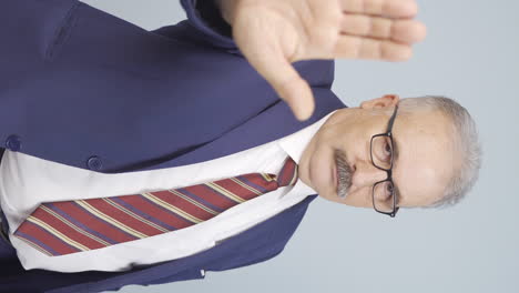 Vertical-video-of-Old-businessman-saying-stop-to-camera.