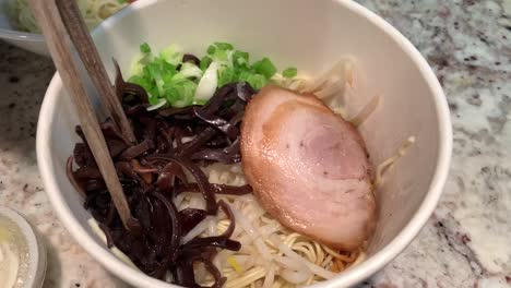 take out japanese ramen noodles topped with sliced pork belly, green onions, bean sprouts, and mushrooms