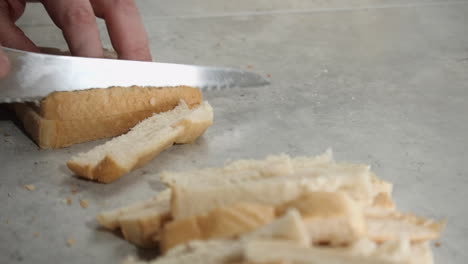 el cocinero corta las costras de las rebanadas de pan blanco con un cuchillo serrado