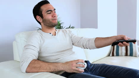 hombre viendo la televisión con una taza de café