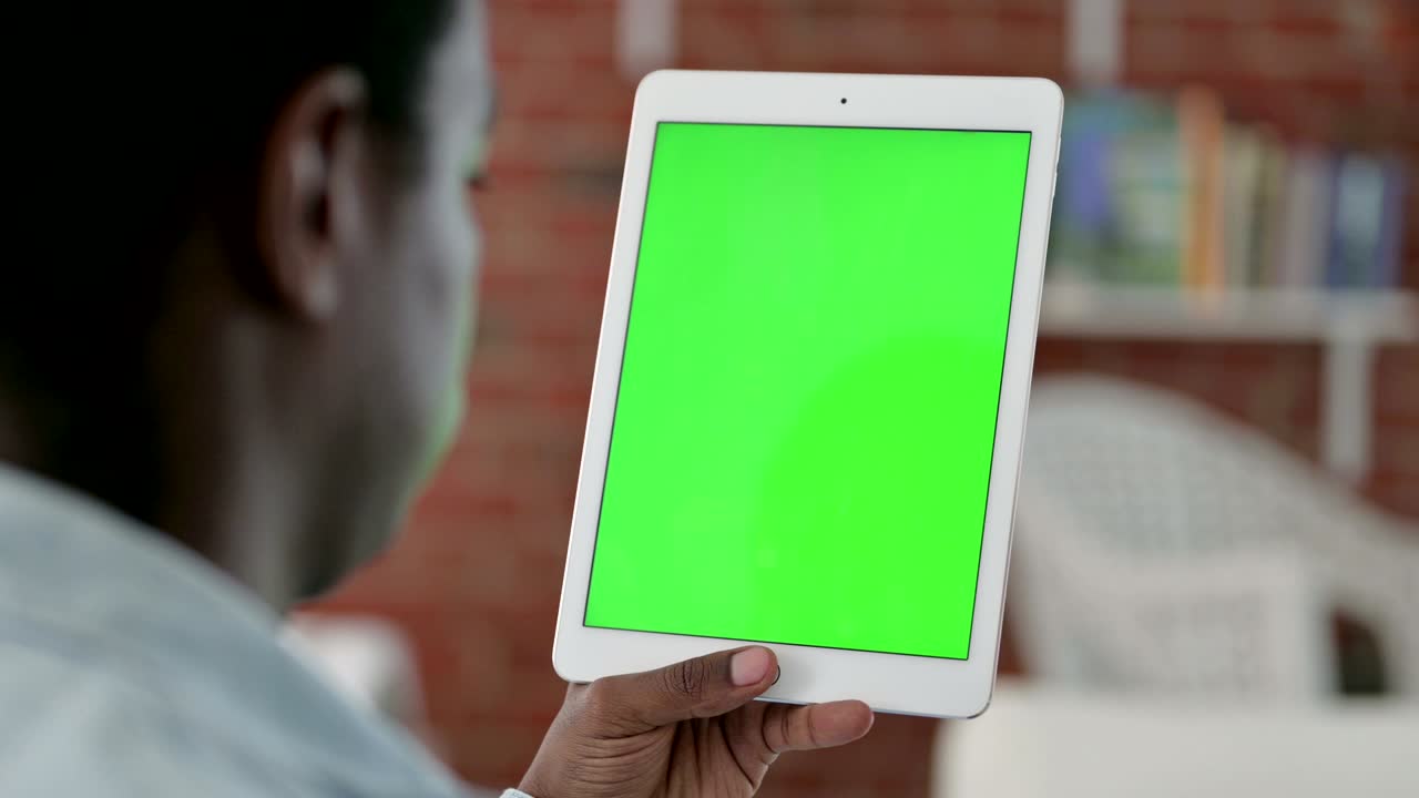 vista trasera de un hombre africano usando una tableta con pantalla cromada