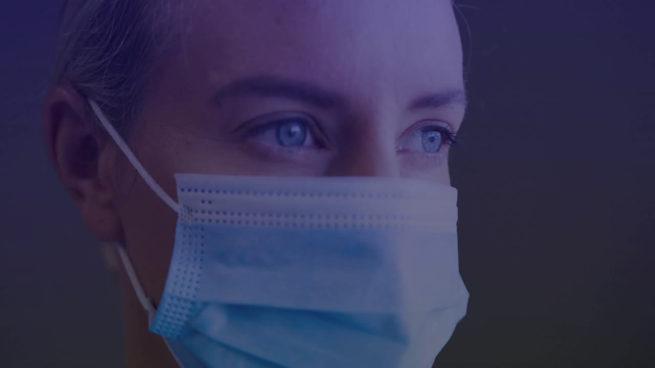 Mujer enmascarada sosteniendo una mirada fija mientras un panel de IU de escaneo de neón analiza las tendencias de datos biométricos