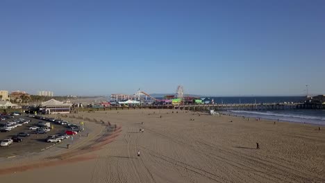 People-on-beach,-parking-lot-in-front-of-Santa-Monica-Pier