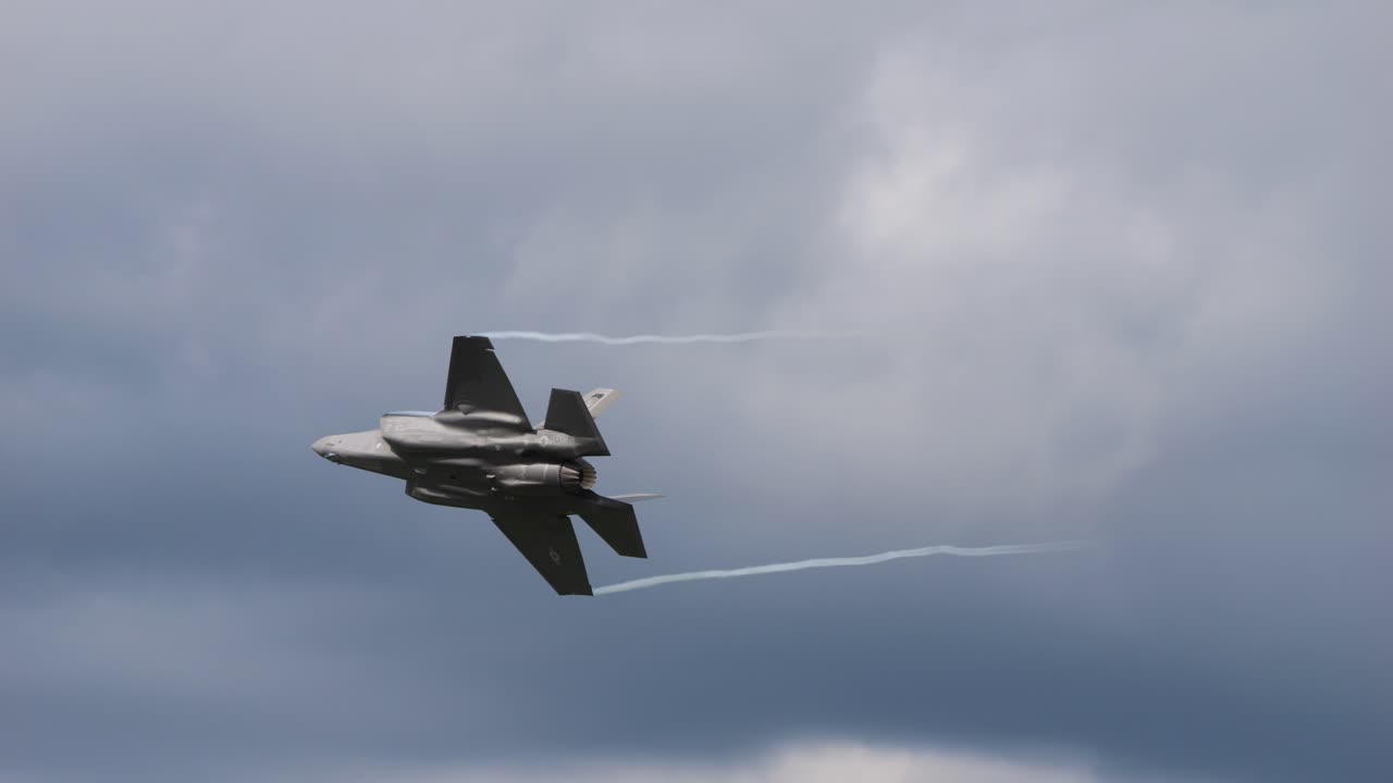 The F-35 fighter plane flies through the air at the air show called Airpower and turns away. You can see the afterburner
