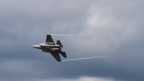 the f-35 fighter plane flies through the air at the air show called airpower and turns away. you can see the afterburner