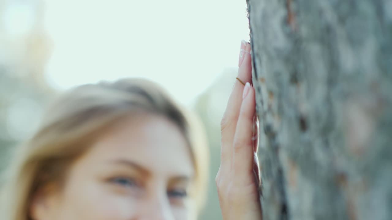 카메라 co를 보고 웃 고 태양에서 나무에 의해 서 있는 아름 다운 젊은 여자의 초상화
