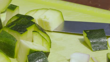 overview of freshly cut organic healthy courgette zucchini with knife on chopping board - 4k food slow motion footage