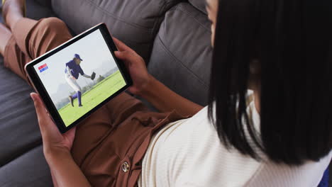 composite of woman sitting at home on couch watching baseball game on tablet