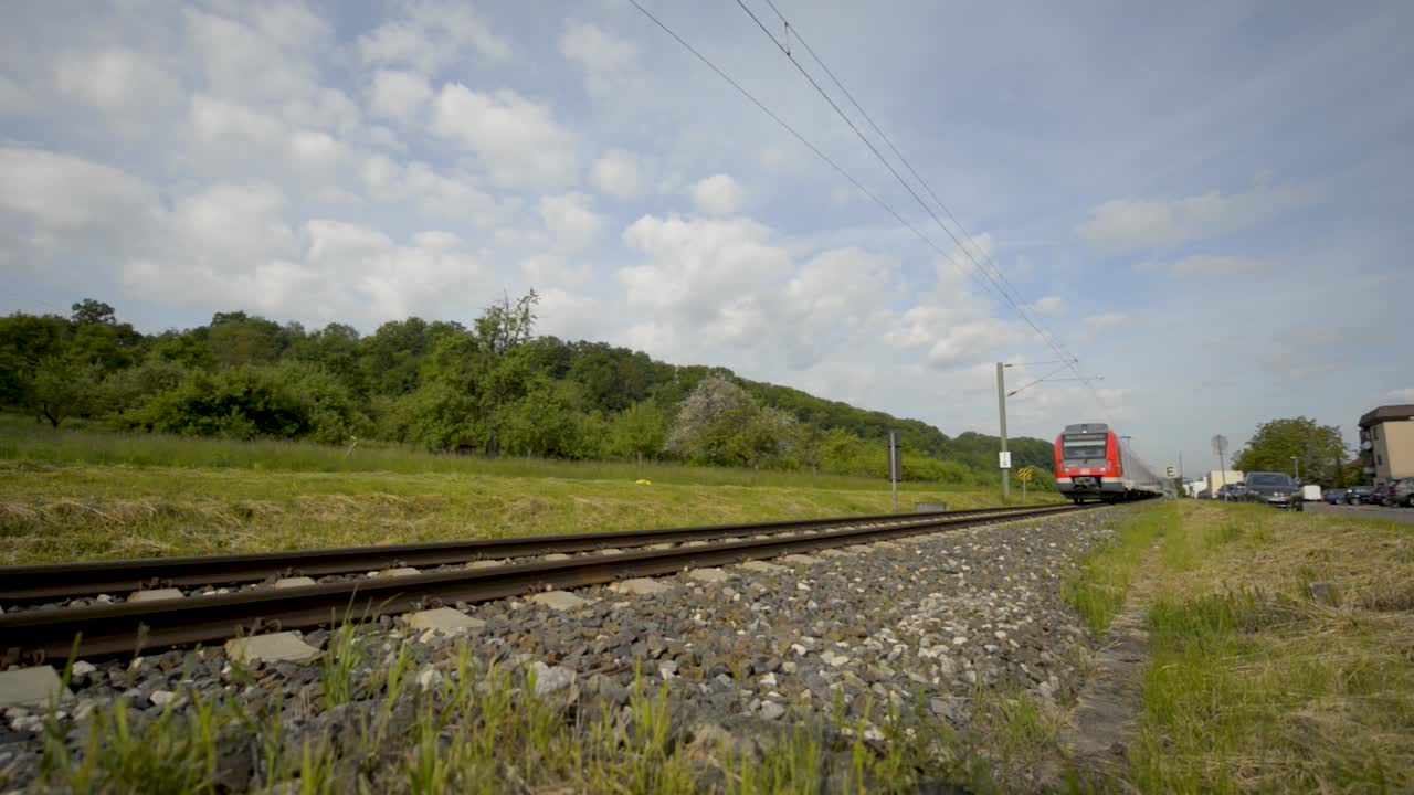 Low-angle shot of a red S-Bahn train traveling through a rural area on a sunny day