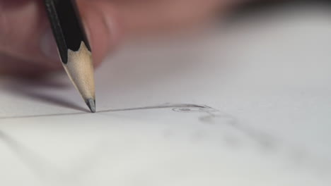 closeup of a hand holding a black pencil drawing a line in a picture