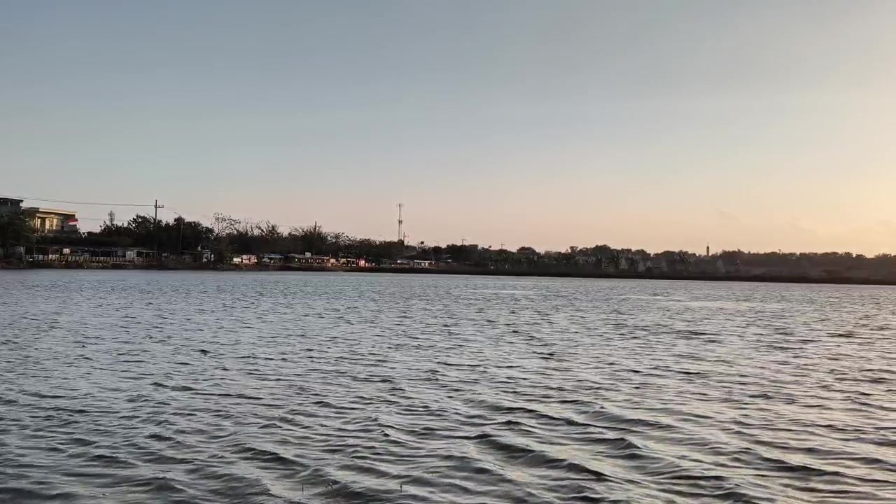 Superficie calma del lago al tramonto con una riva distante