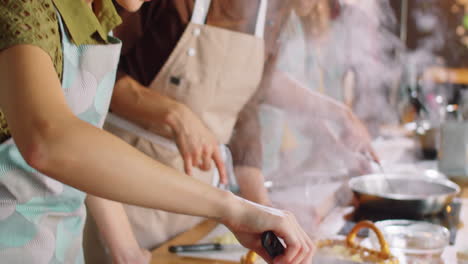 woman cooking pasta and chatting with chef during culinary class