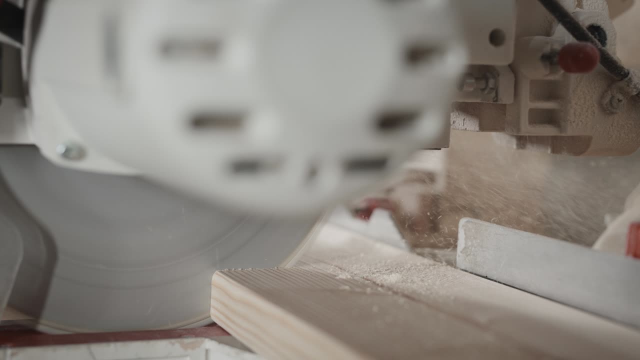 в деревообрабатывающей мастерской. рабочий режет доску с помощью пилы