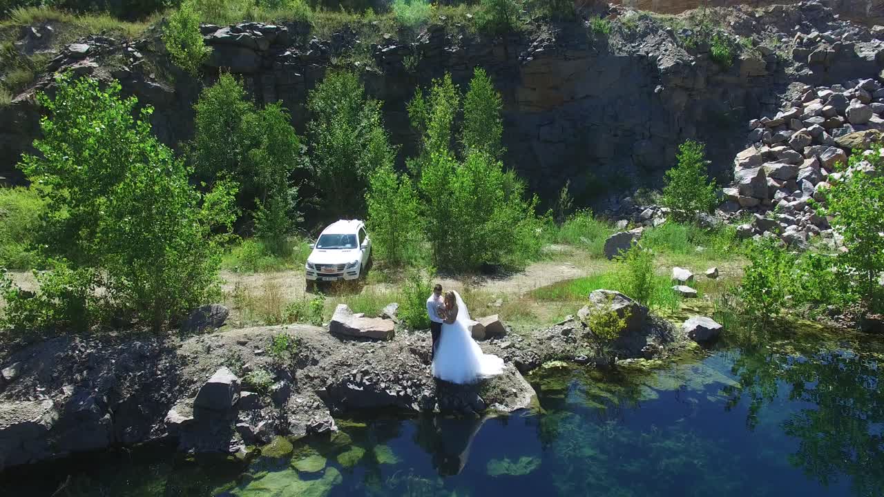 Bruidspaar Wandelt Bij Water. Luchtfoto van een liefdevol bruidspaar dat wandelt en kust bij het water