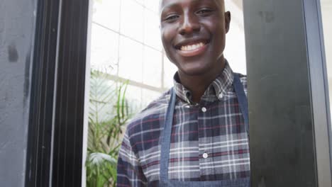 Portrait-of-african-american-male-coffee-shop-owner-opening-up-shop,-slow-motion