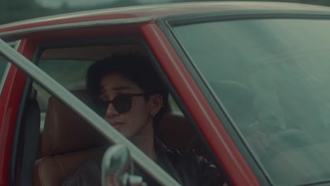 man driving a vintage red car