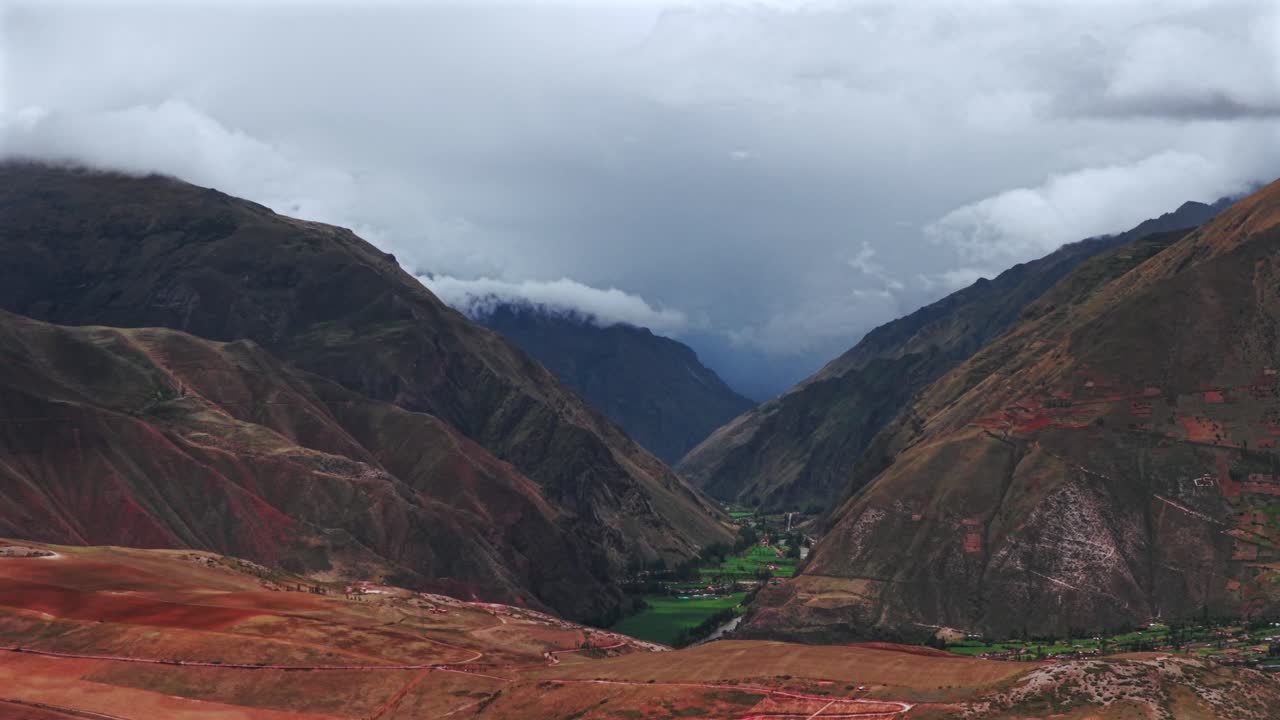Valle Sacra di Ollantaytambo, miniera di sale di Maras, Perù, vista aerea da drone, terra rossa, Salineras de Maras, stagione delle piogge, nuvoloso, Ande peruviane, Monte Patacancha, Moray, Chicón, Ancopacha, regione di Cusco, movimento in avanti