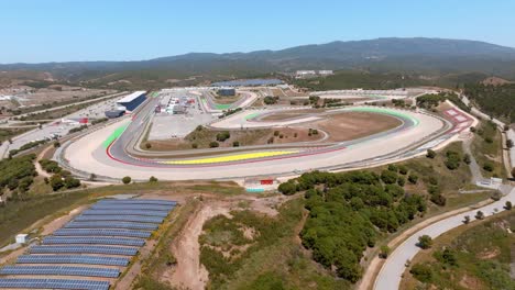 Drone-pullback-to-sky-reveals-portimao-circuit-and-red-yellow-lanes,-blue-sky-day