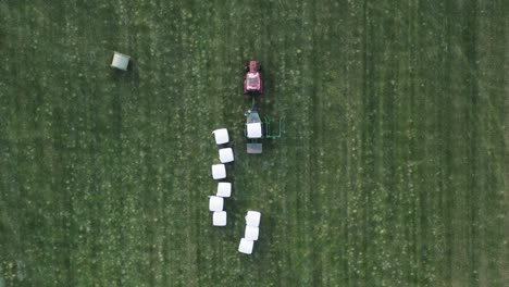 wrapping hay bale with white plastic foil on green grass field in iceland