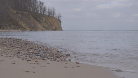 tourists at the shore of gdynia redlowo beach with overcast sky on baltic sea coast, poland