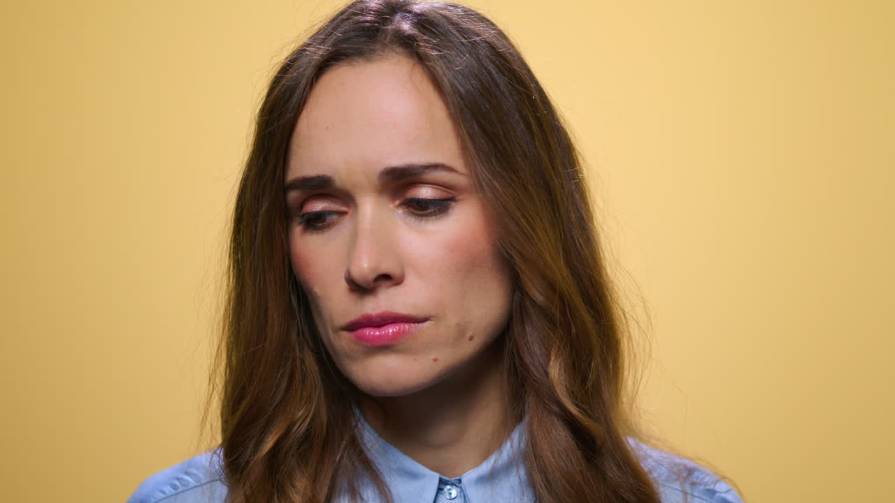Upset business woman looking at camera. Unhappy girl on yellow background