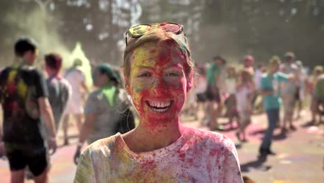 young happy girl in colourful powder is smiling on holi festival in daytime in summer, watching at camera, color concept, emotional concept