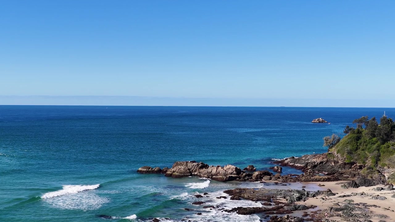 Ampia veduta aerea di onde oceaniche turchesi che si infrangono su una costa rocciosa a South West Rocks