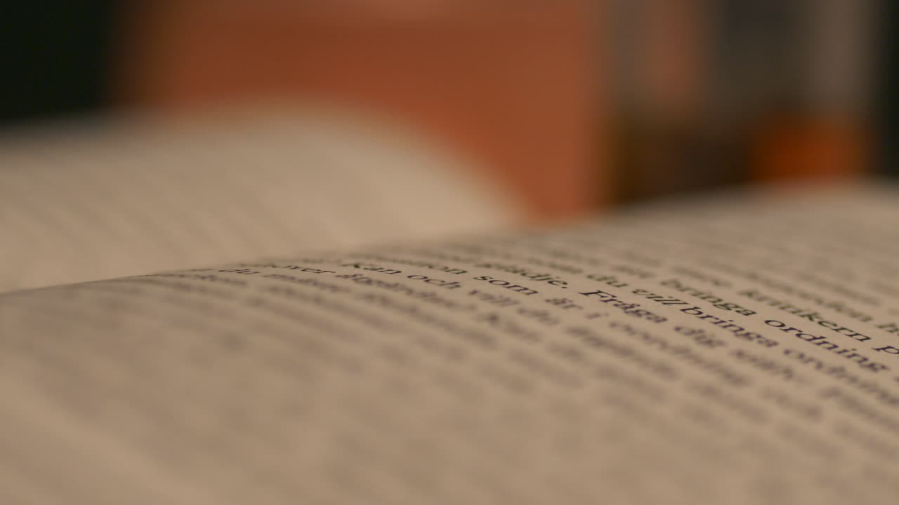 primer plano del libro, pasando a la página siguiente, idioma extranjero apenas visible, tiro deslizante de la plataforma rodante