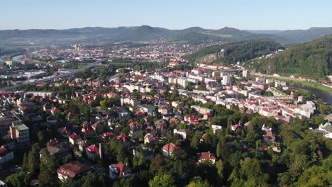 drone zoom in capturing decin city skyline, rooftops and distant hills in warm morning light