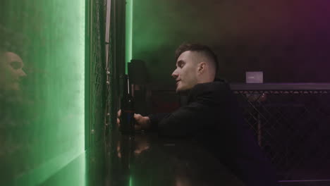 young man drinking beer while sitting alone at disco club 1