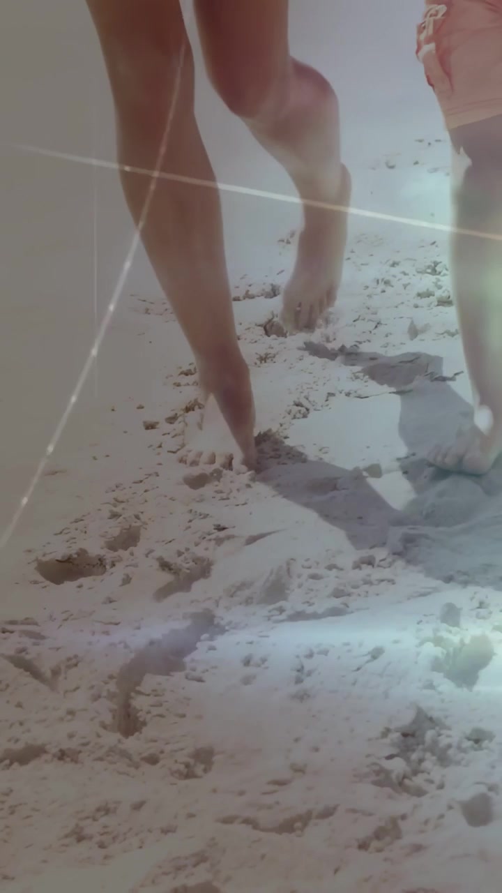 Video verticale: Adulti di mezza età che camminano, una gamba che inizia a fare passi sulla sabbia, HUD che traccia la passeggiata in famiglia.