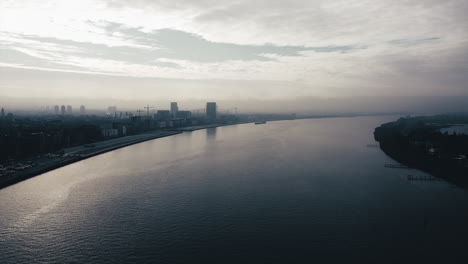aerial shot above scheldt river and cargo ship passing in background after sunset