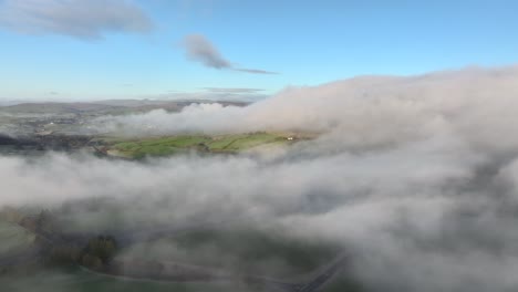 flying above drifting low cloud and misty landscape with m6 motorway below at dawn in winter