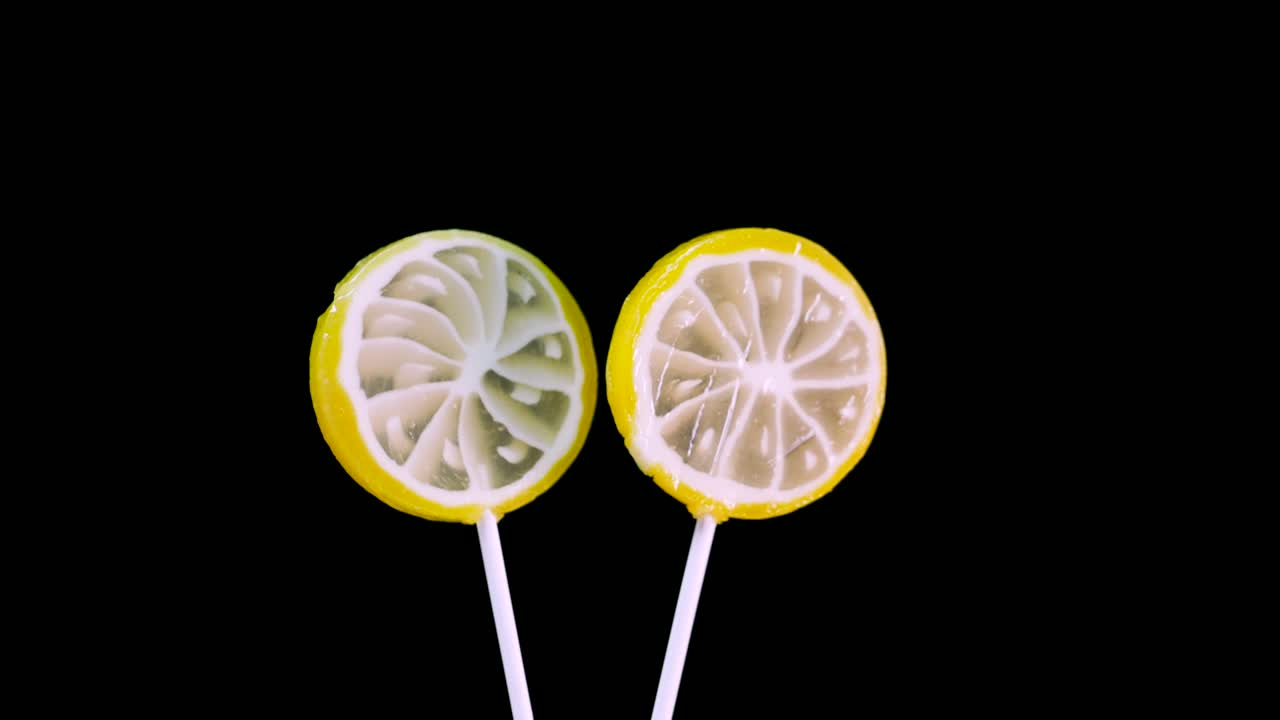 Lollipop spinning on a black background, baby lemon candy. Caramel sweets