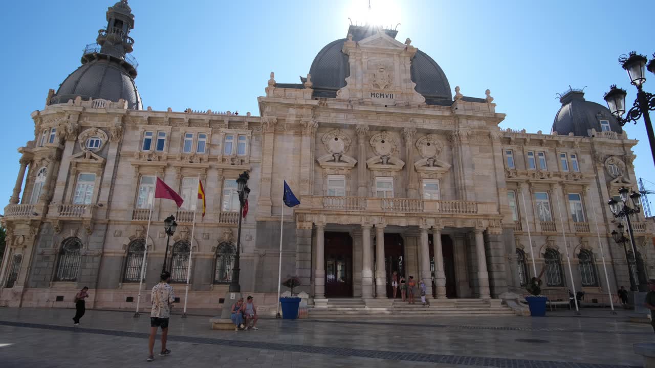 The Palacio Consistorial stands proudly with Spanish flags waving in the air, accentuating the building’s historic charm and symbolizing national pride against a majestic backdrop.